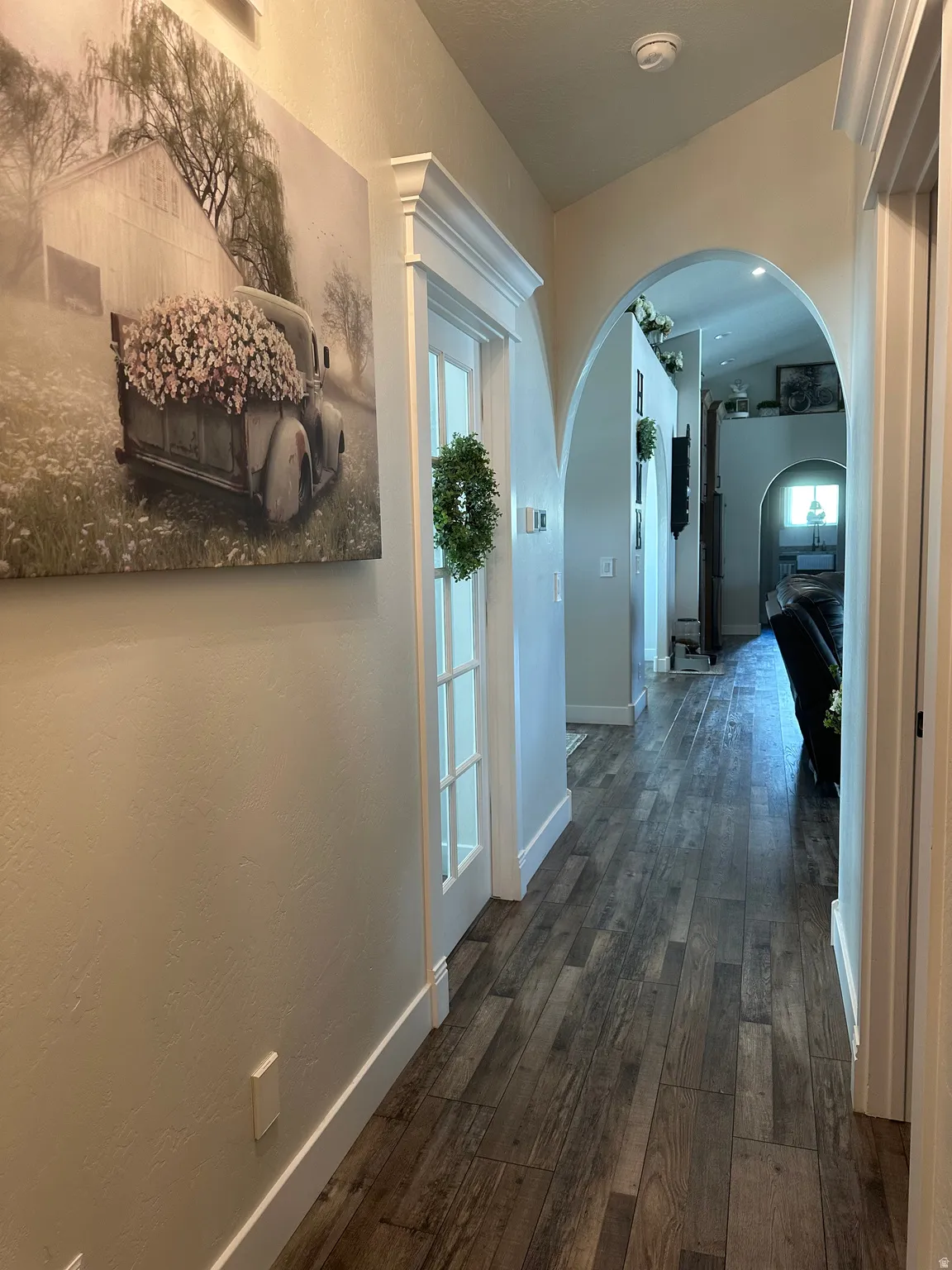 Hallway featuring arched walkways, dark wood-type flooring, and a textured wall