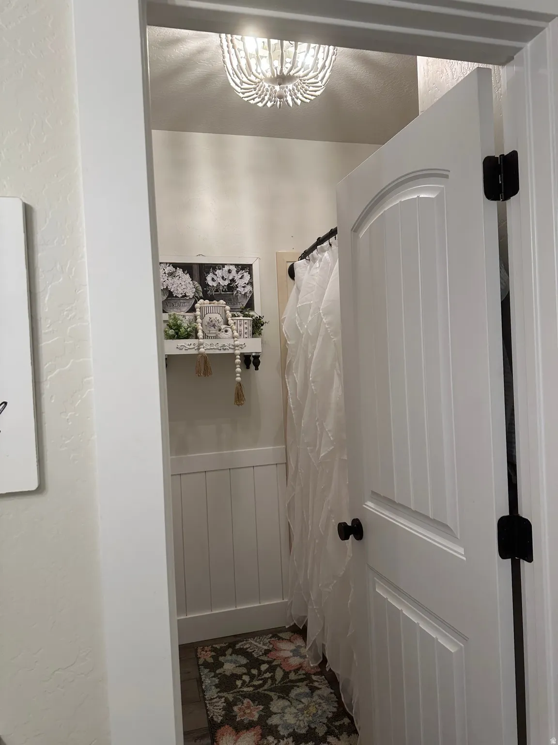 Bathroom featuring a wainscoted wall, curtained shower, and a textured wall