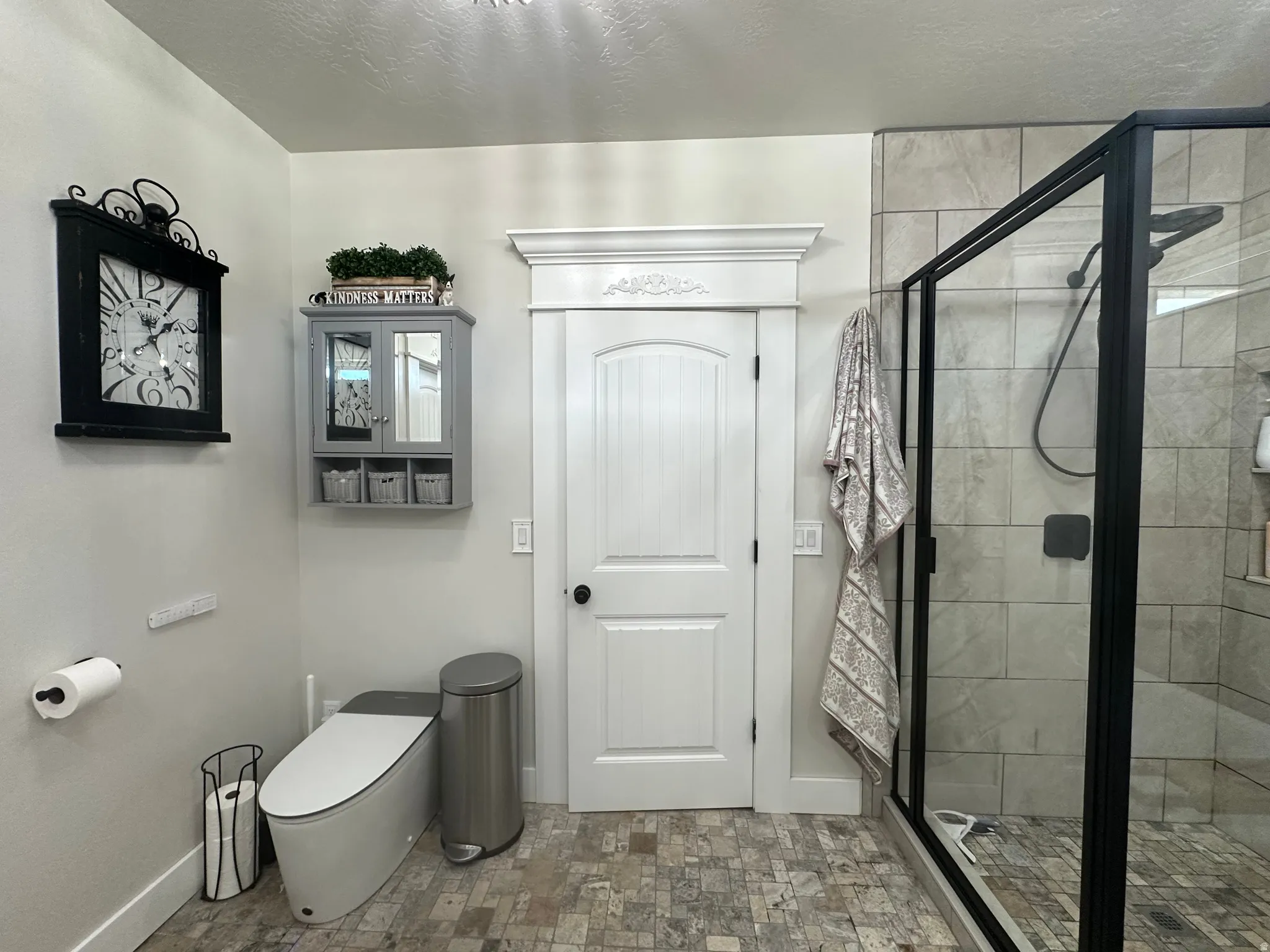 Full bath with a shower stall, a textured ceiling, and stone finish flooring