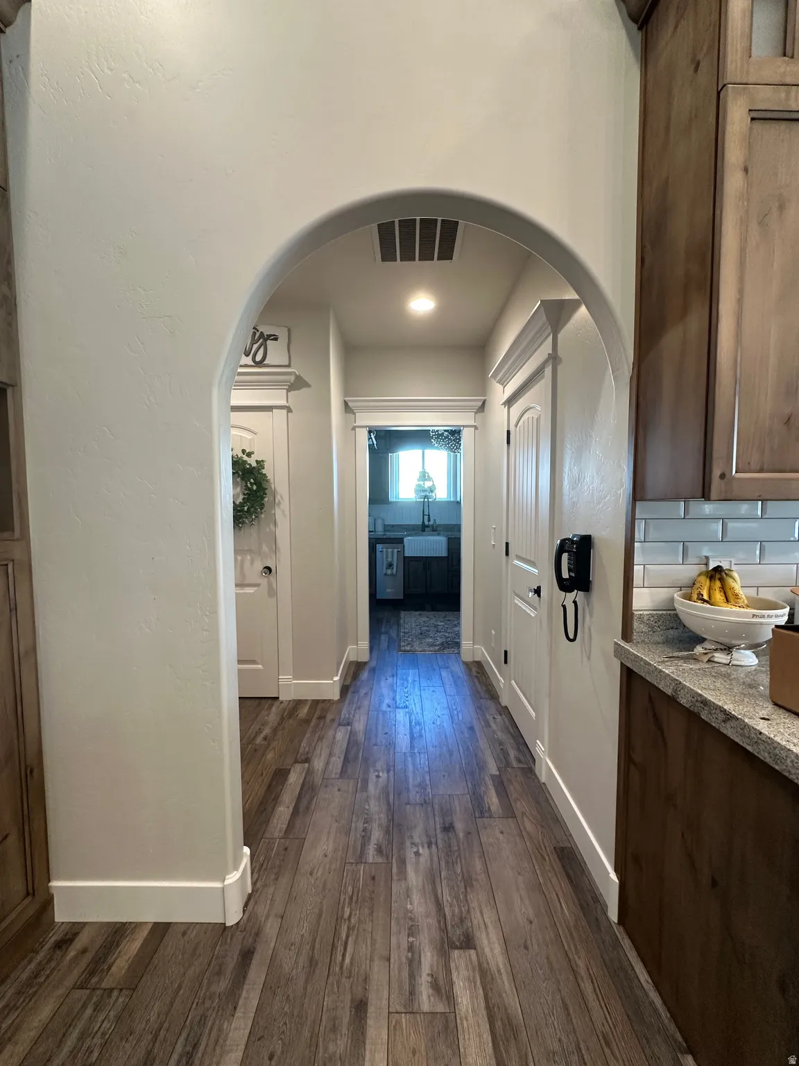 Hall with dark wood-type flooring and arched walkways