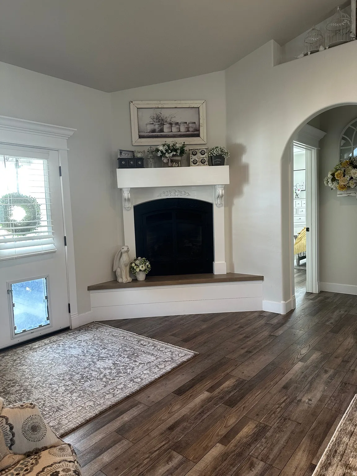 Living room featuring arched walkways, a premium fireplace, vaulted ceiling, and dark wood-style flooring