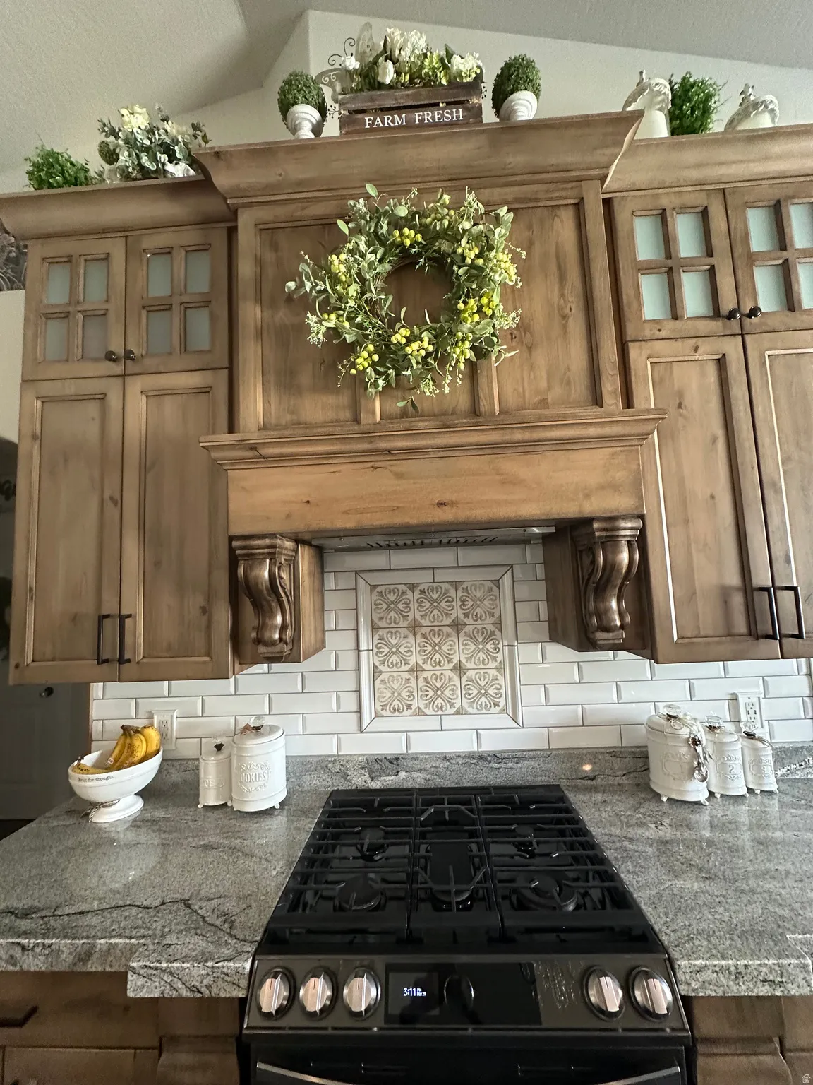 Kitchen with glass fronted cabinets, range with gas stovetop, and dark stone counters