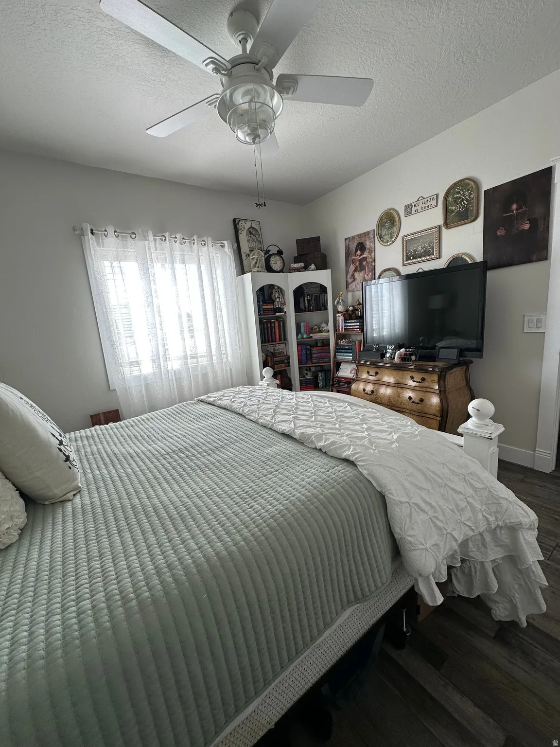 Bedroom featuring dark wood-style floors, a textured ceiling, and ceiling fan
