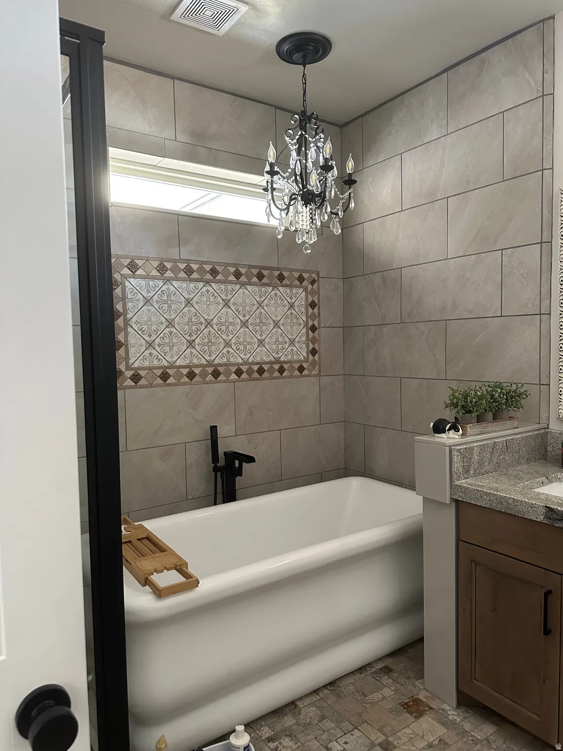 Full bathroom with vanity, a freestanding tub, suspended lighting, and tile walls