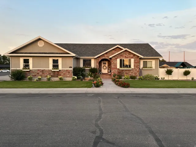 Single story home featuring stucco siding, stone siding, and a shingled roof