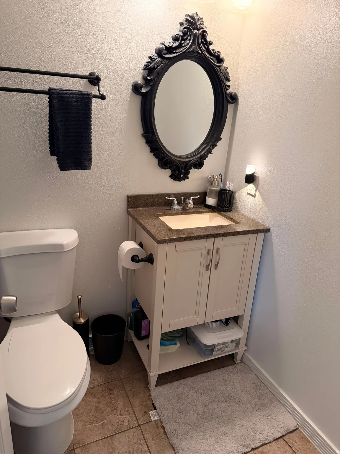 Bathroom with vanity, light tile patterned floors, and a textured wall