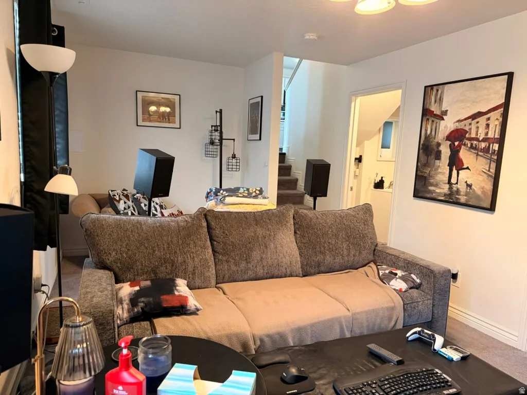 Carpeted living area featuring stairway and baseboards