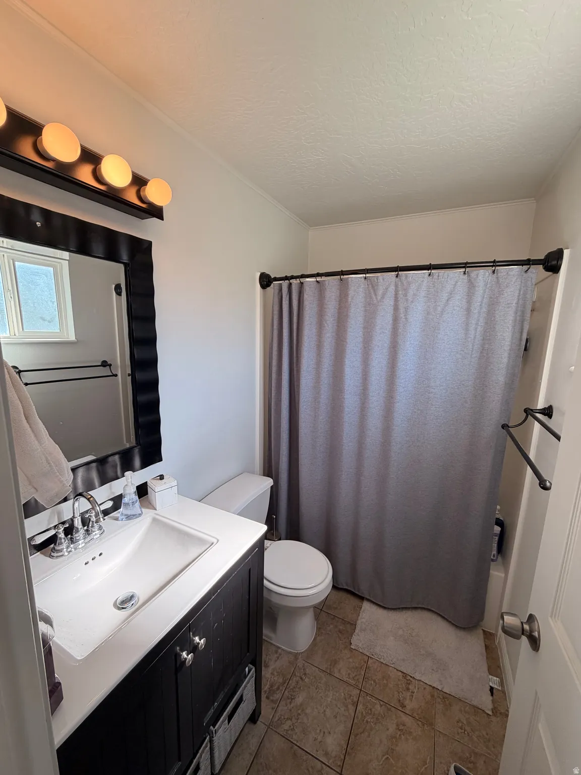 Full bath featuring vanity, shower / bathtub combination with curtain, a textured ceiling, and light tile patterned floors