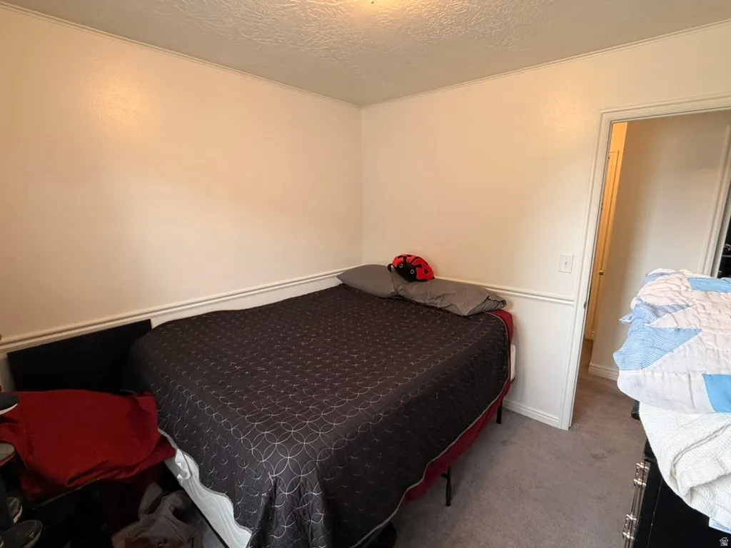 Carpeted bedroom with a textured ceiling and baseboards
