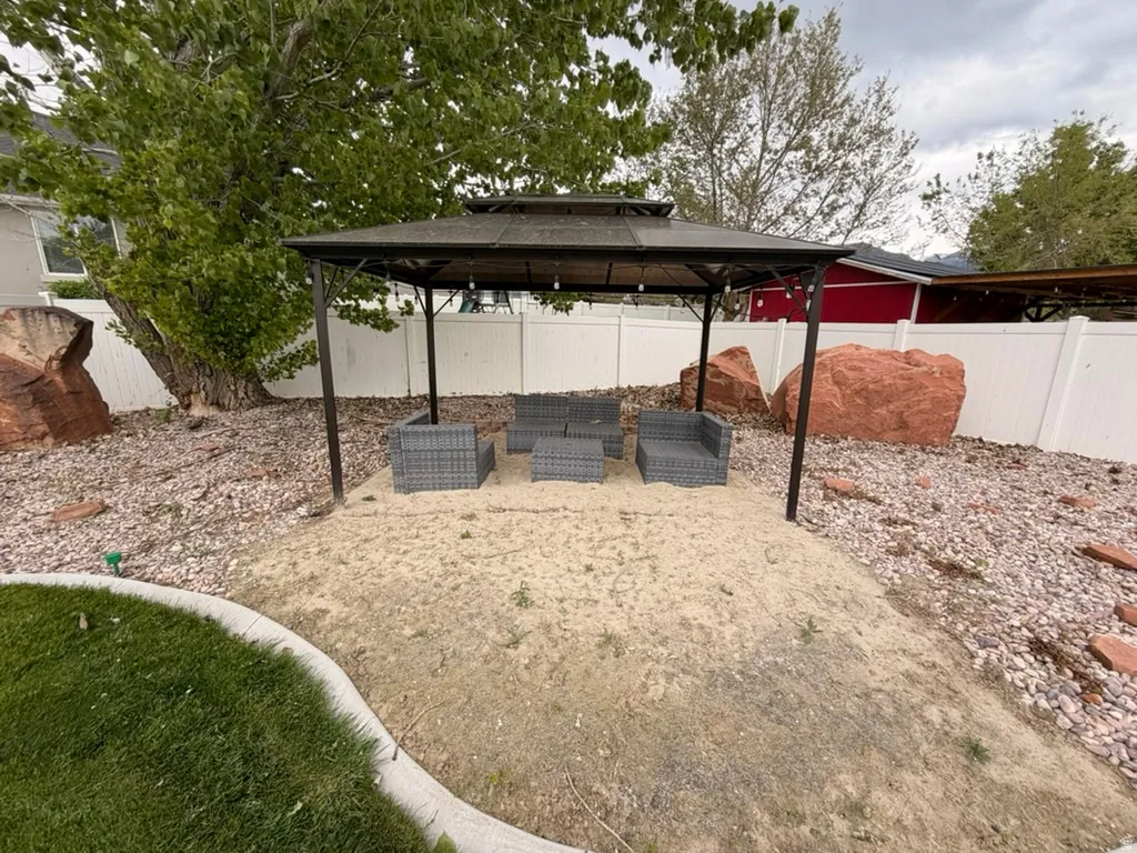 Fenced backyard featuring a patio area, an outdoor hangout area, and a gazebo