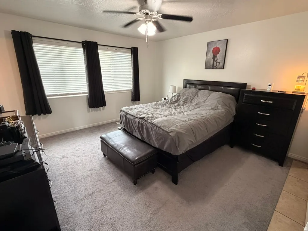Bedroom featuring a textured ceiling, a ceiling fan, and light carpet