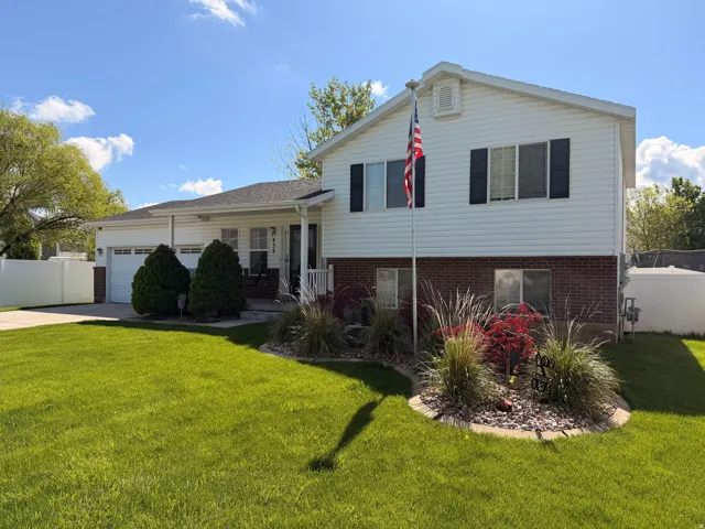 Split level home featuring a garage, driveway, brick siding, and covered porch