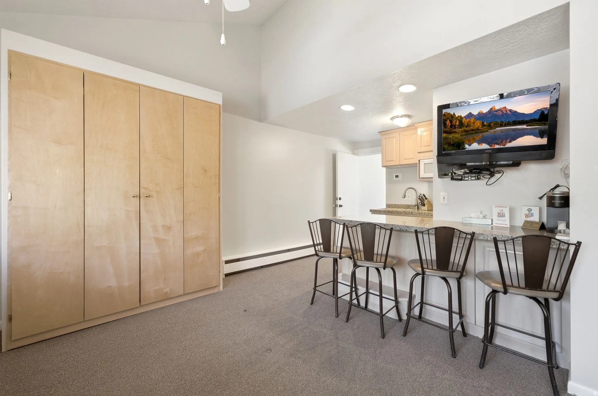 Integrated kitchenette featuring a granite-style countertop, light wood-finish cabinetry, and a stainless steel sink