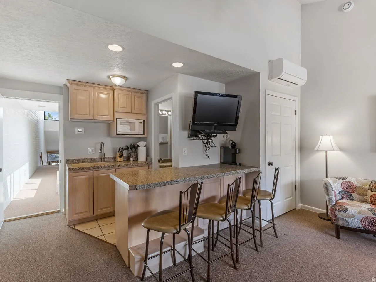 Kitchen featuring light carpet, a breakfast bar area, light wood finish cabinets, a peninsula, and white microwave