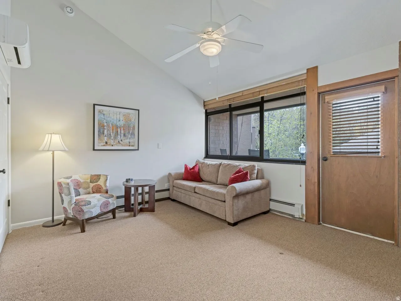 Living area featuring vaulted ceiling, light colored carpet, a ceiling fan, and a baseboard radiator