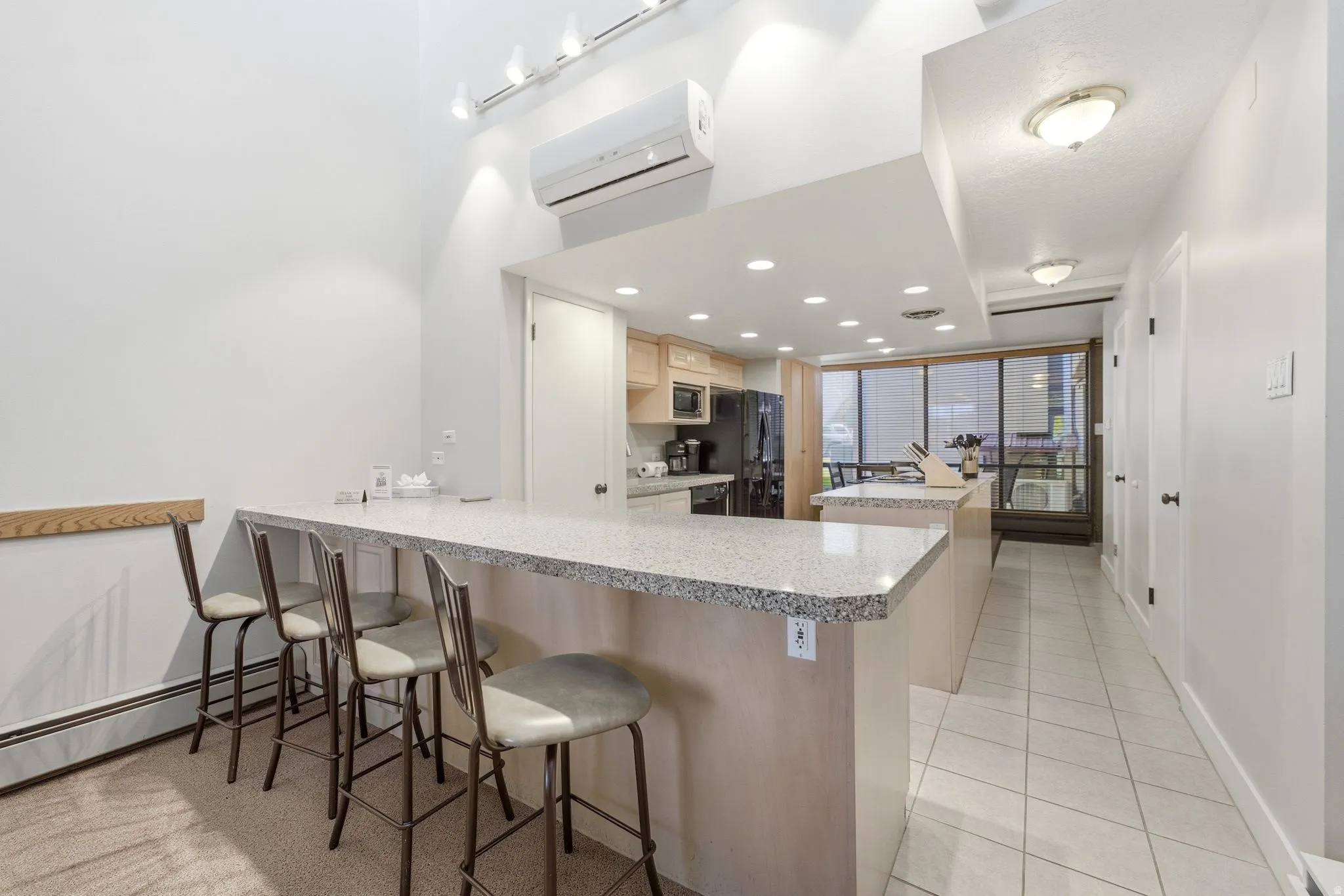 Kitchen featuring a stone-look breakfast bar with seating, recessed lighting, wood cabinetry, and a full suite of appliances