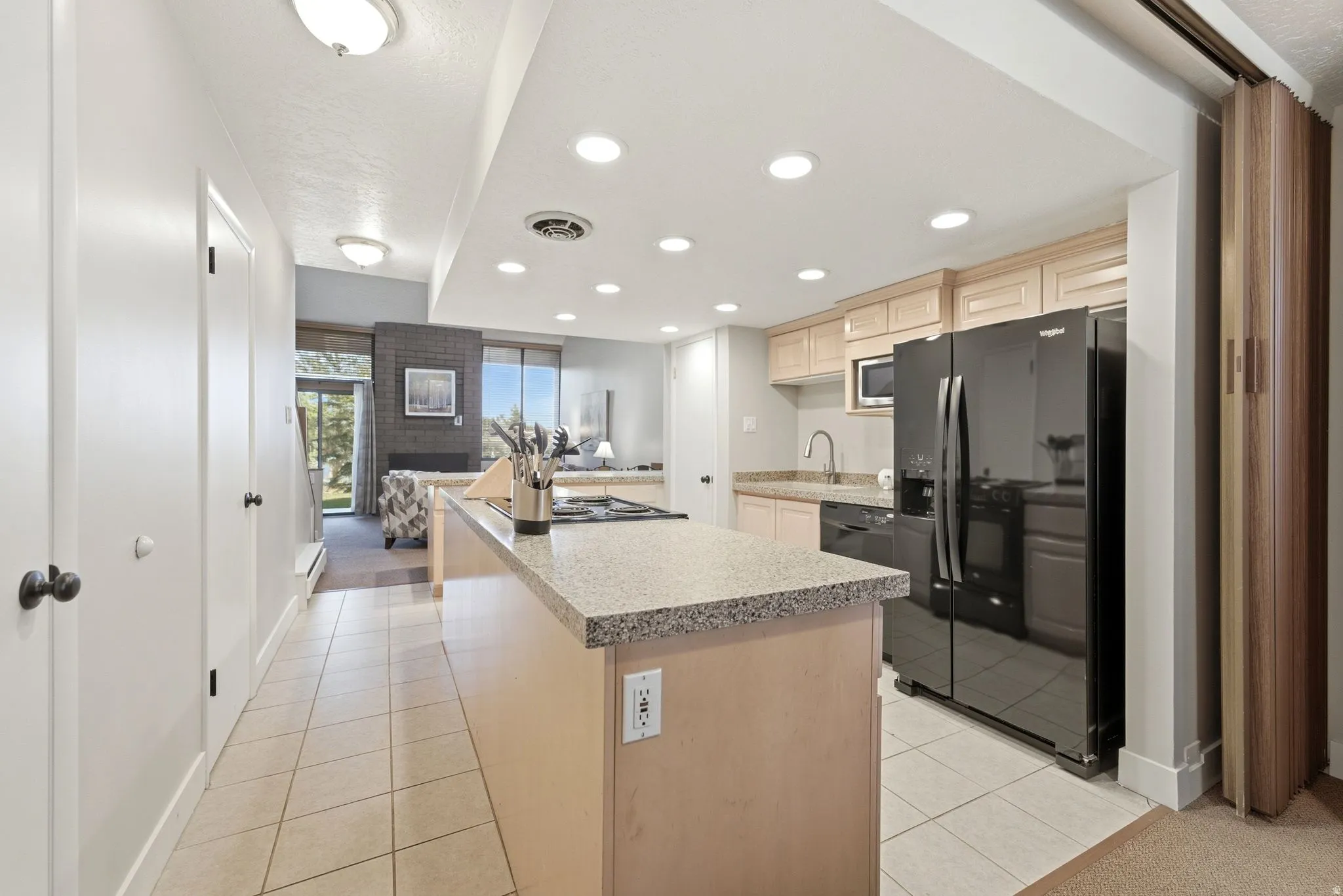 Kitchen featuring a large island with a cooktop, light wood cabinetry, stone-finish countertops, and recessed lighting