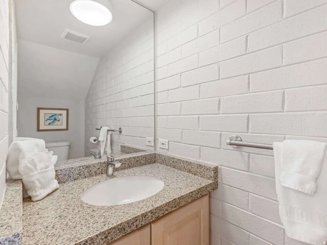 Half bathroom featuring vanity, vaulted ceiling, and concrete block wall