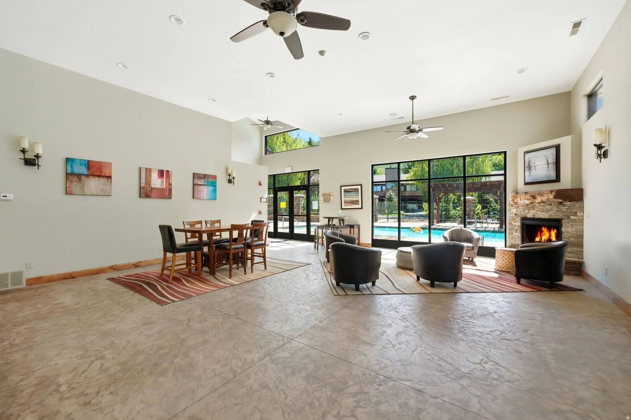 Spacious common area featuring an expansive fireplace with stacked stone surround, large transom windows, and durable patterned flooring