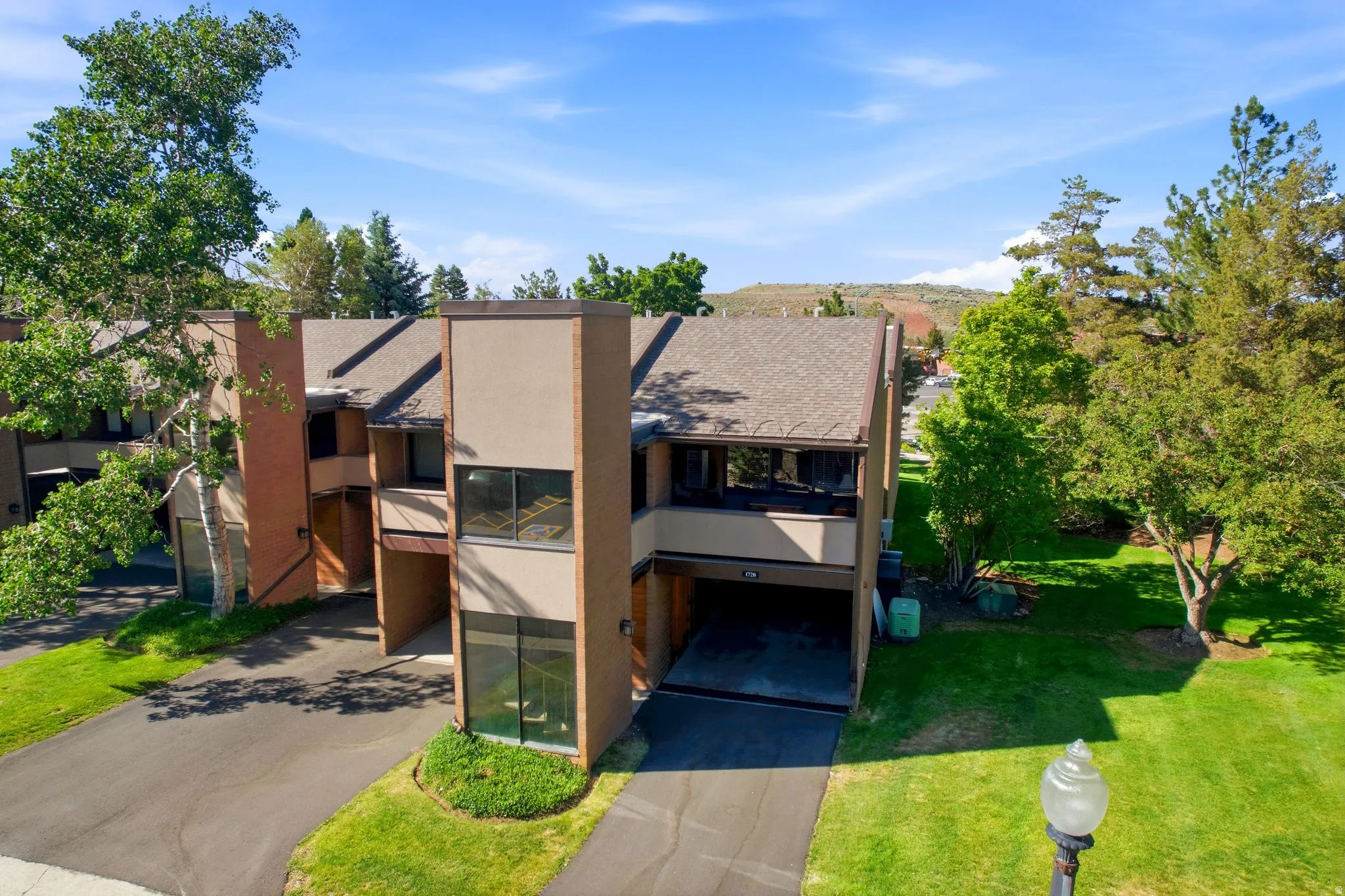 Multi-level townhome featuring a muted earth-tone exterior and a shingle roof