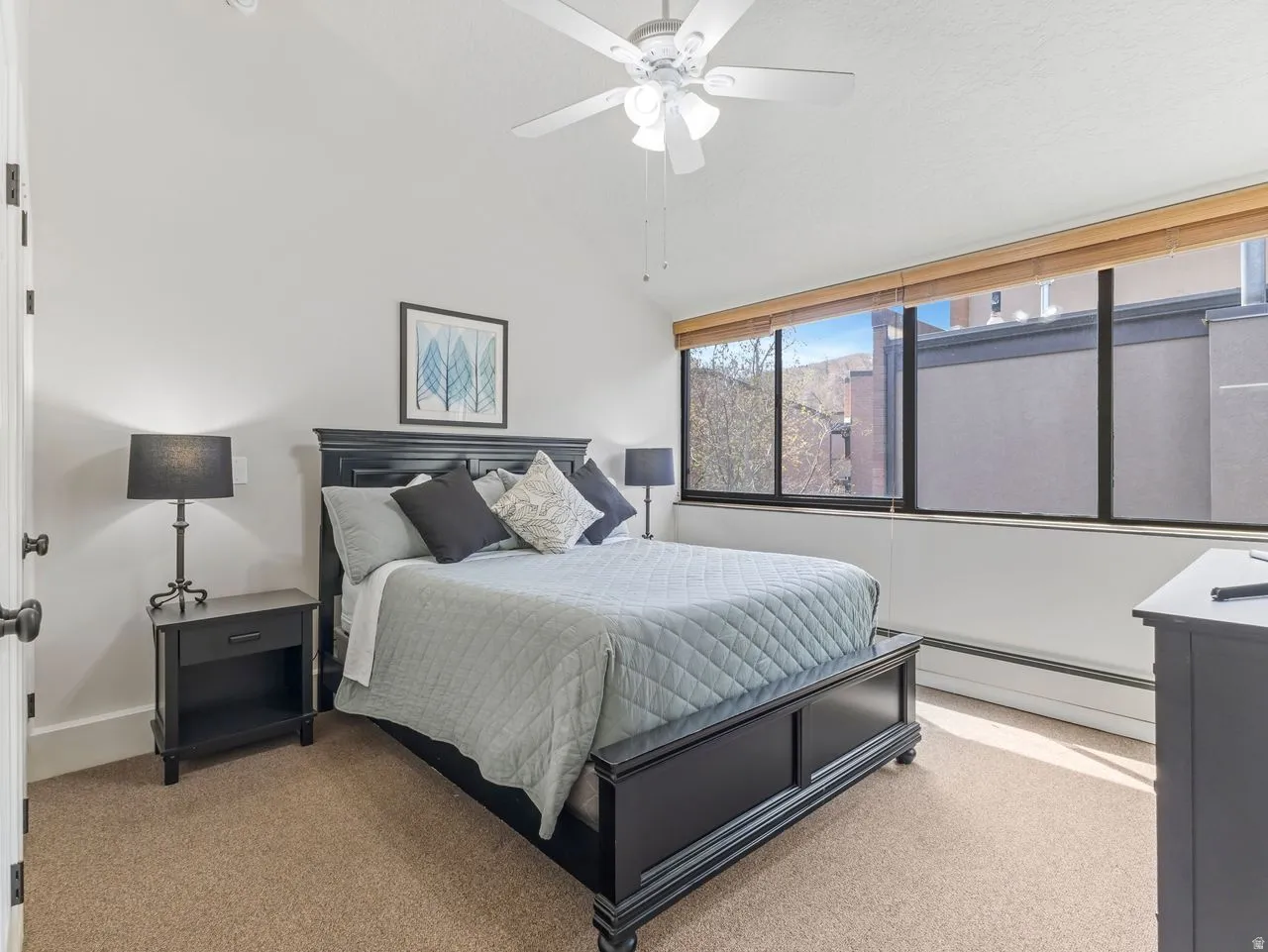 Bedroom featuring vaulted ceiling, baseboard heating, a ceiling fan, and light colored carpet