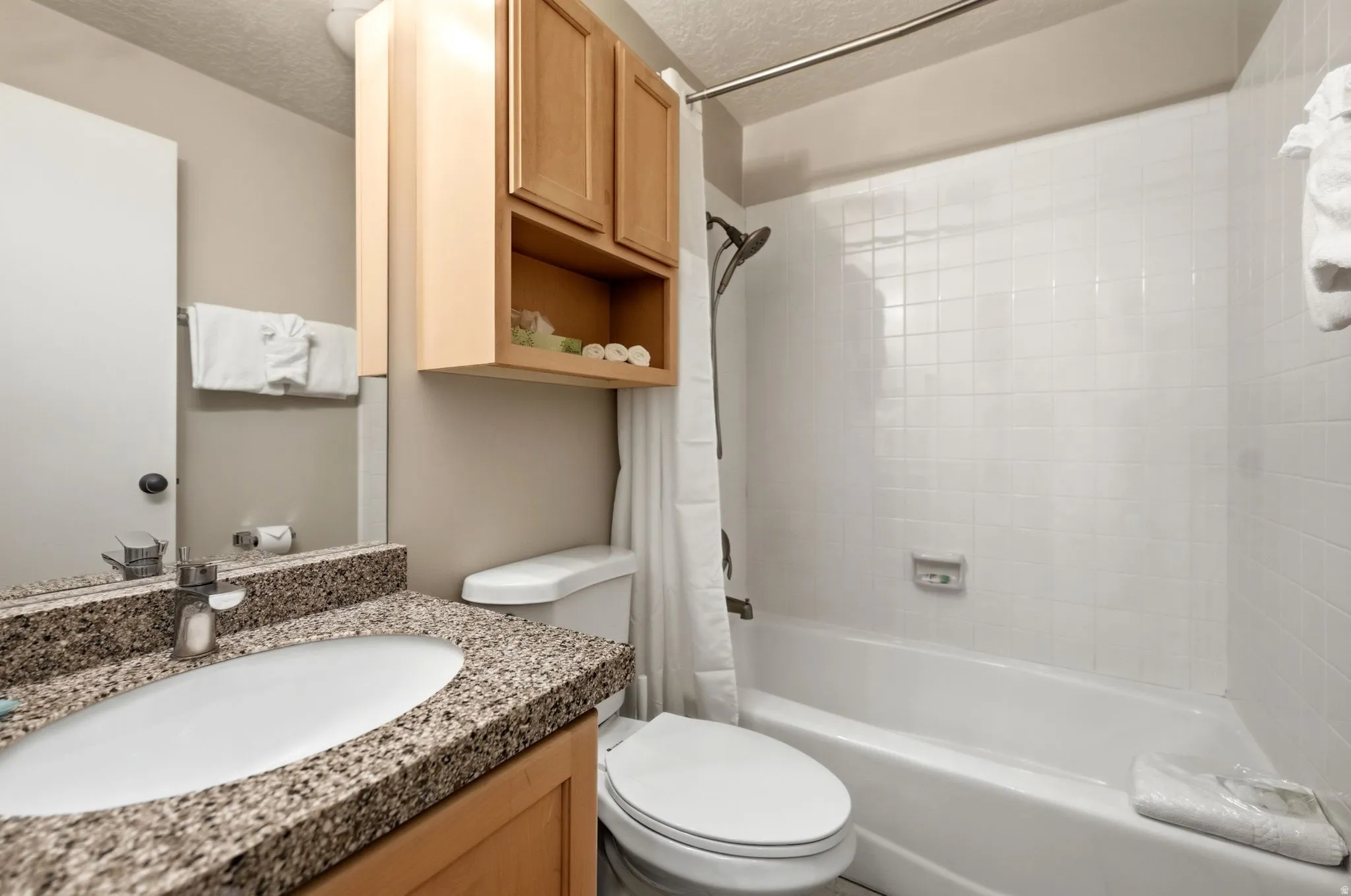 Bathroom vanity featuring a vessel sink, speckled countertop, and wood-finish cabinetry