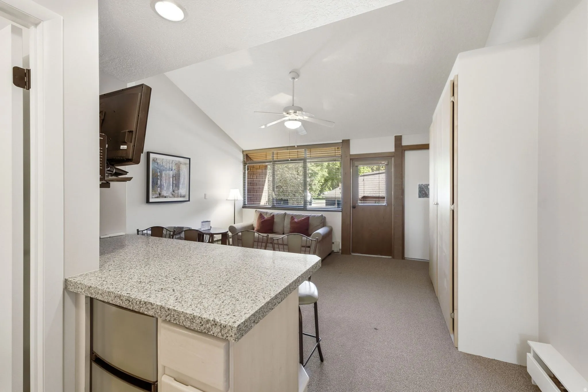 Open-concept living area with a vaulted ceiling and textured carpeting