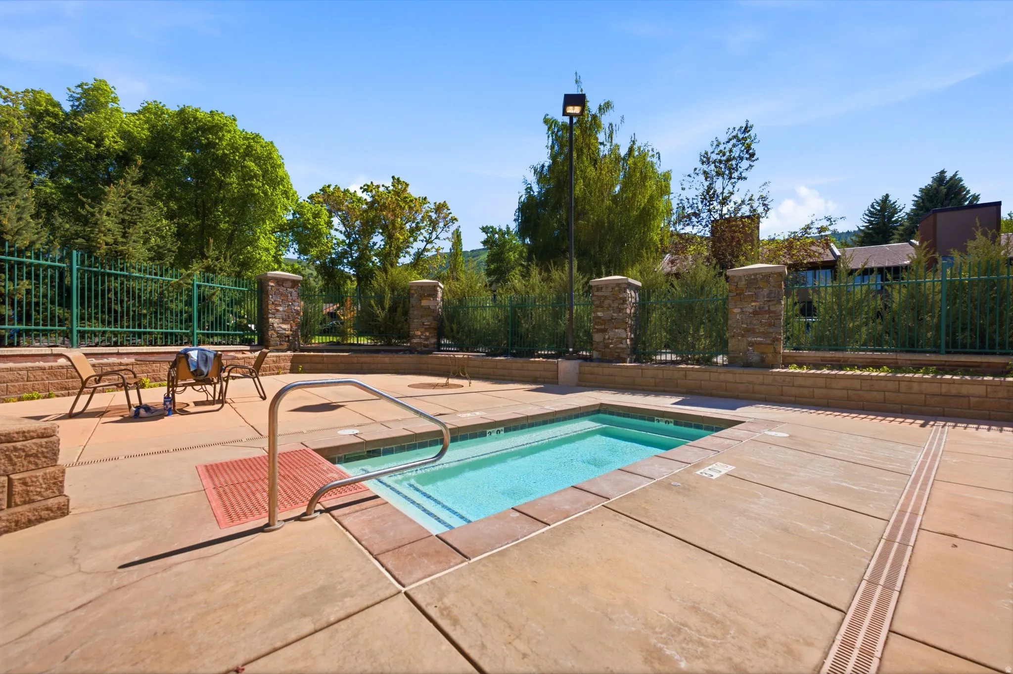 In-ground spa with a built-in entry stair, surrounded by a concrete patio
