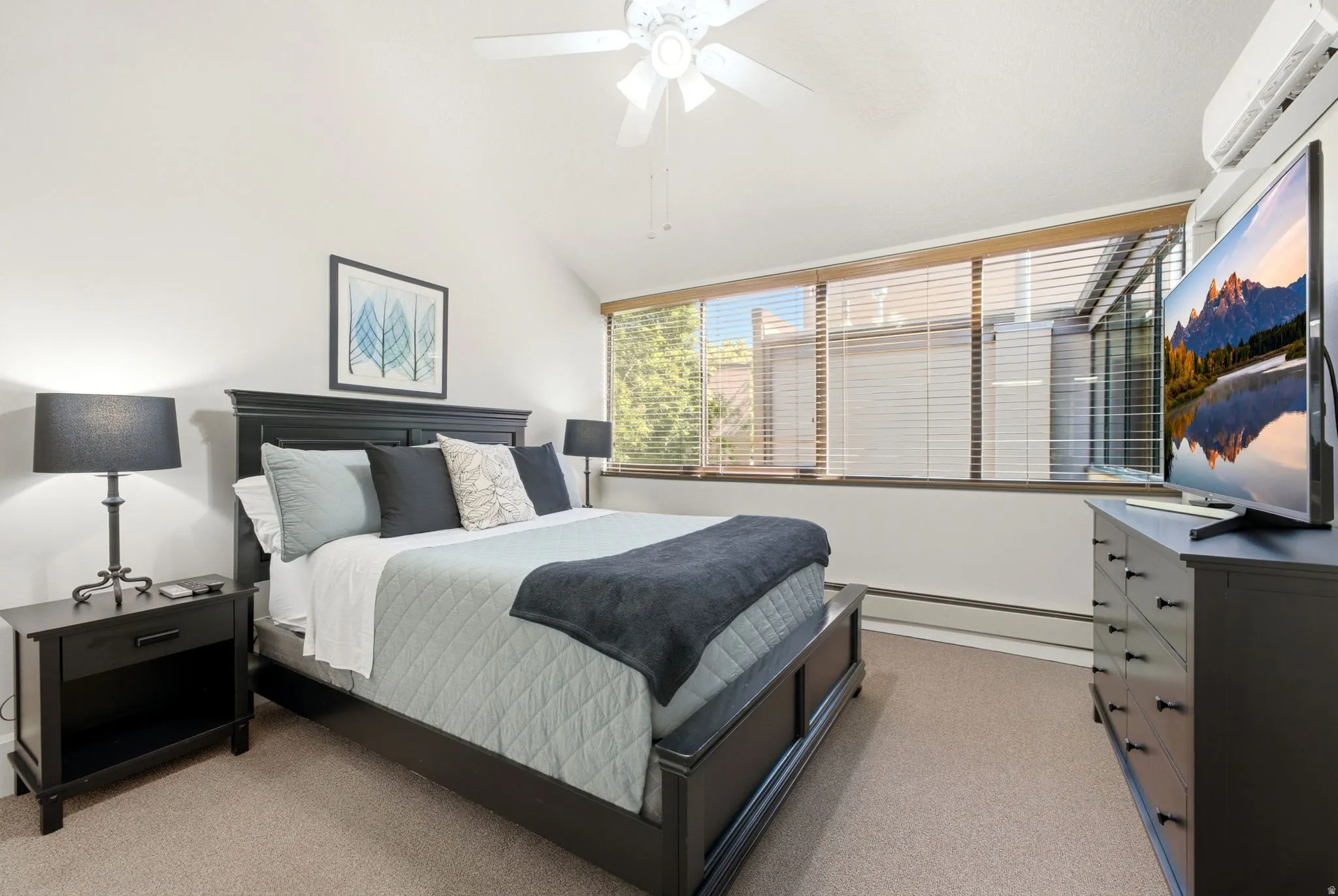 Carpeted room with a vaulted ceiling and a ceiling fan