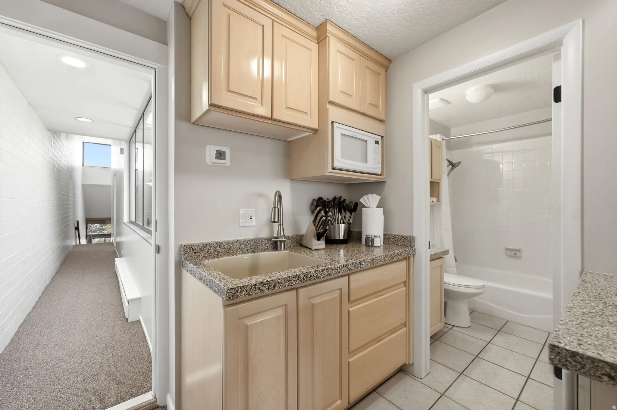 Compact kitchen area featuring wood-finish cabinetry, speckled countertop, and a built-in microwave