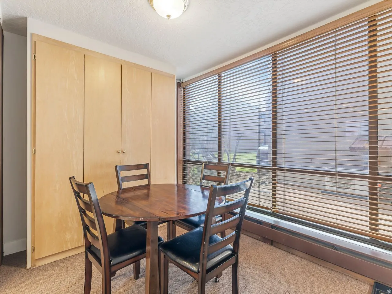 Dining room featuring healthy amount of natural light, light colored carpet, and a textured ceiling