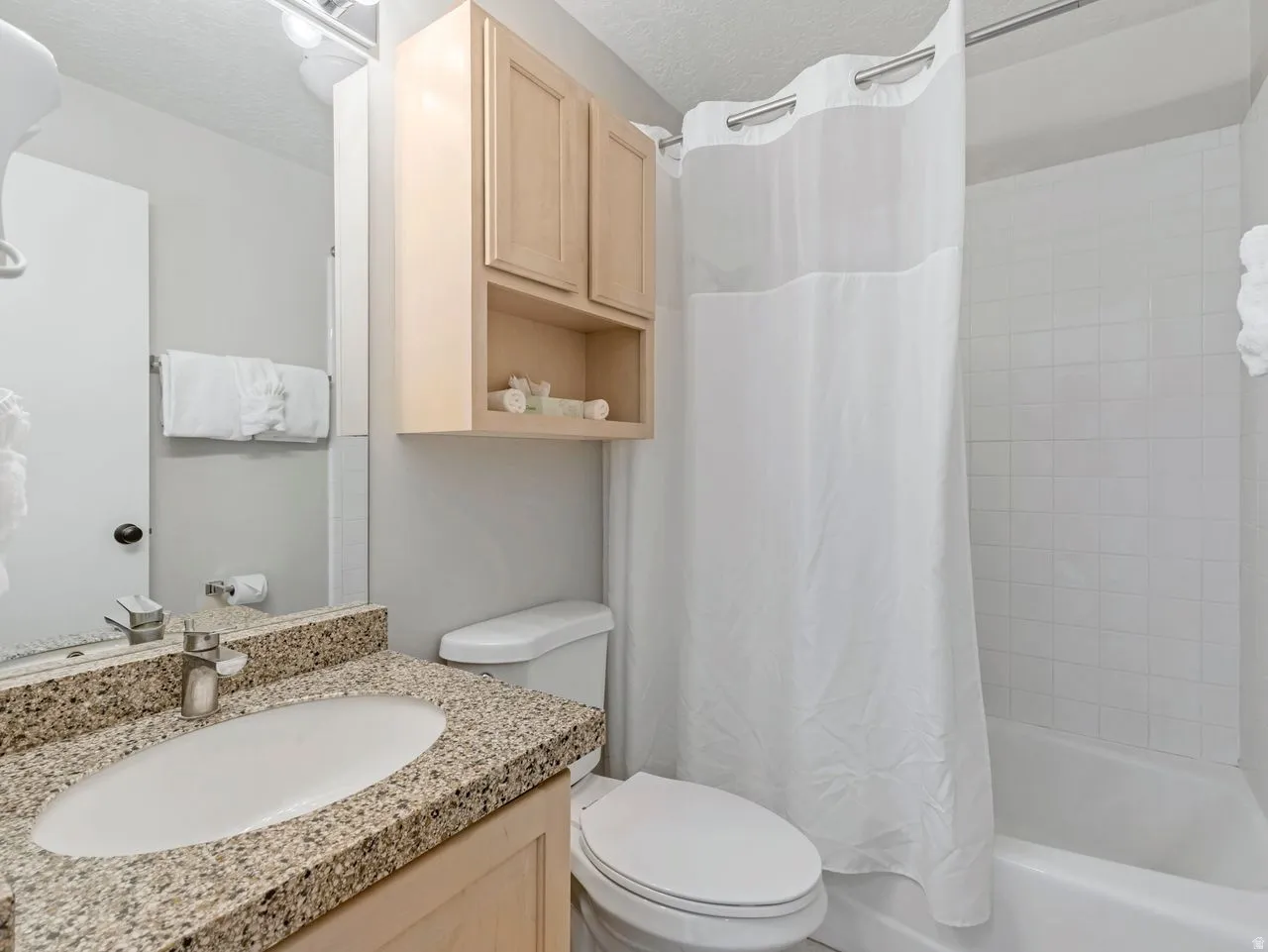 Bathroom with vanity, shower / tub combo, and a textured ceiling