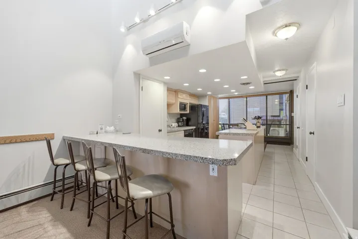 Kitchen featuring a stone-look breakfast bar with seating, recessed lighting, wood cabinetry, and a full suite of appliances