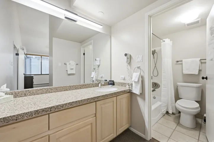 Bathroom featuring a light-toned vanity with a speckled countertop, an integrated sink, and an expansive mirror