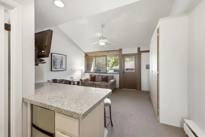 Open-concept living area with a vaulted ceiling and textured carpeting