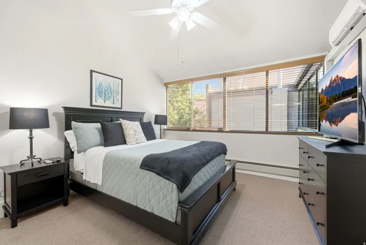 Carpeted room with a vaulted ceiling and a ceiling fan