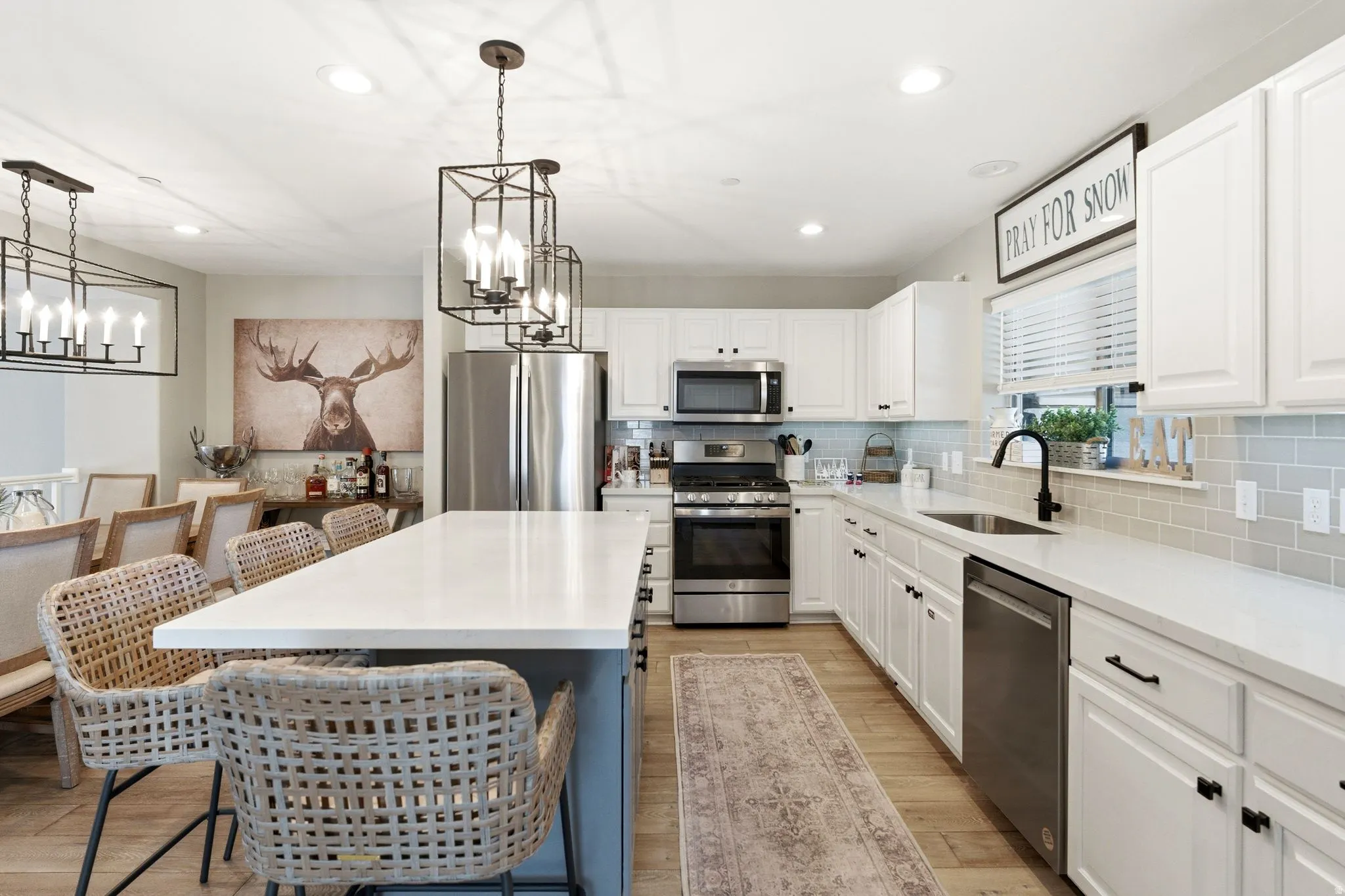 Kitchen featuring stainless steel appliances, a kitchen breakfast bar, a center island, two tone color scheme, and suspended lighting
