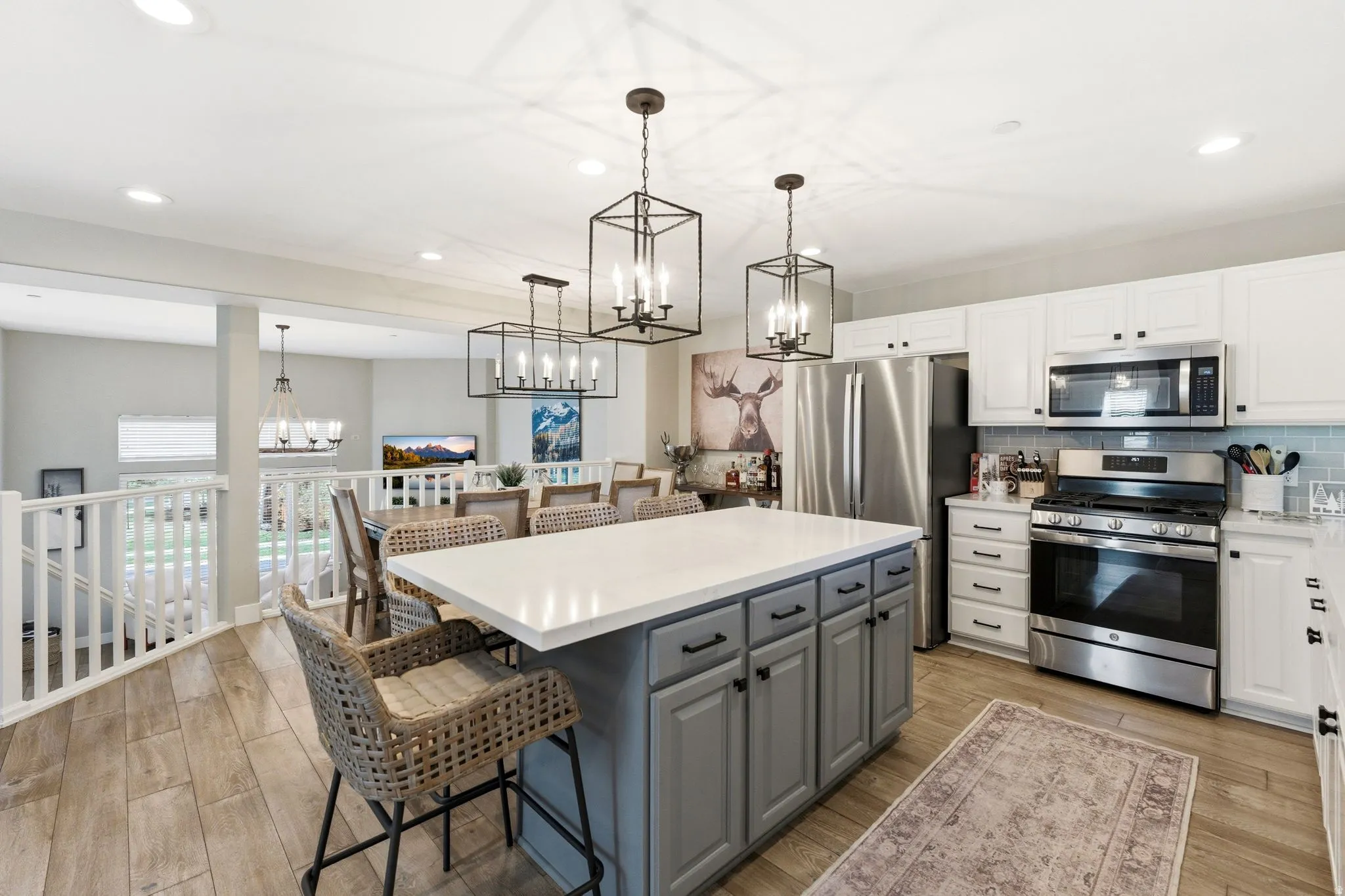 Kitchen with two tone cabinets, stainless steel appliances, a breakfast bar, light wood finished floors, and a kitchen island