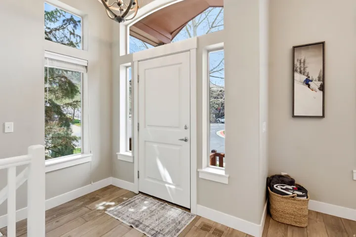 Entryway with suspended lighting, light wood-style floors, and lofted ceiling