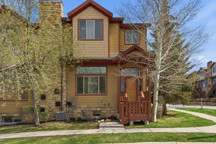 View of front of home with a front yard, a chimney, and stone siding