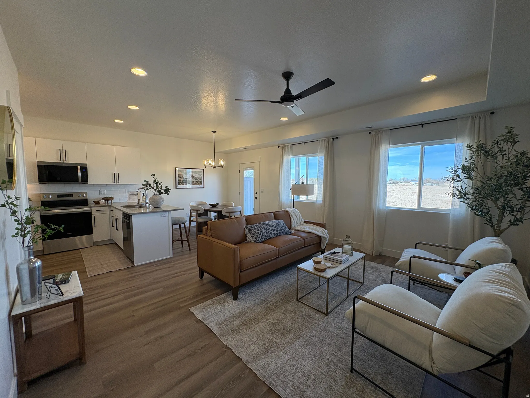 Living room with hanging lights, dark wood-style flooring, and a ceiling fan