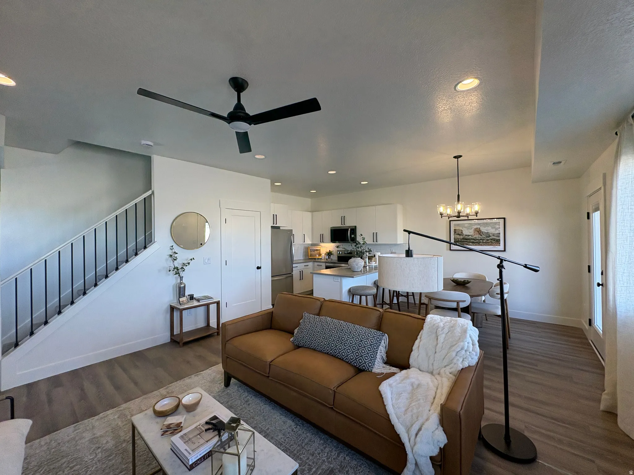 Living area featuring dark wood-style flooring, suspended lighting, and ceiling fan