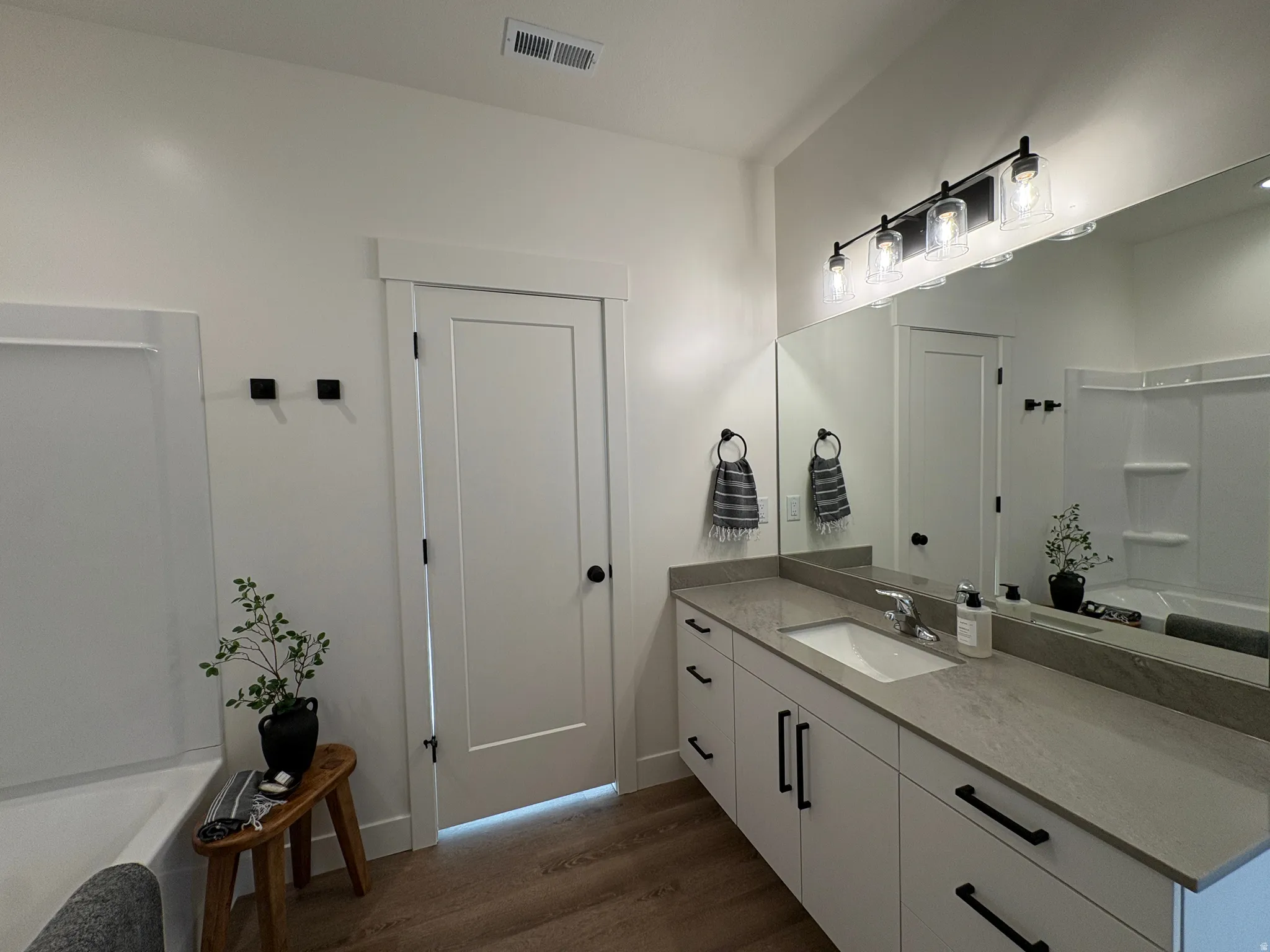 Bathroom with vanity, dark wood-style floors, and bathtub / shower combination