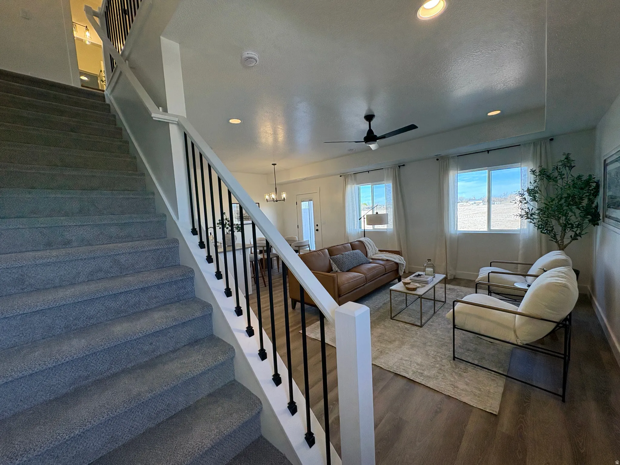 Staircase featuring wood finished floors, a ceiling fan, and a chandelier