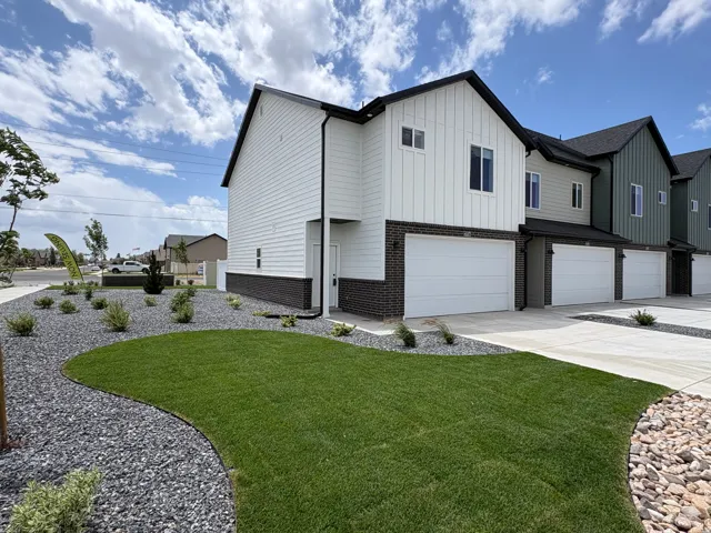Modern townhome exterior featuring vertical and horizontal siding, dark brick accents, and a dark shingled roof