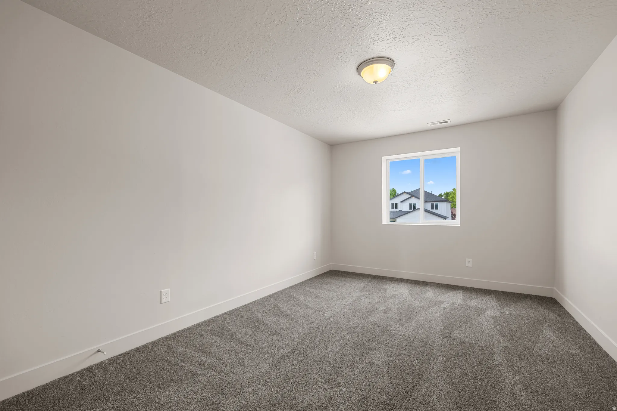 Empty room with carpet floors and a textured ceiling