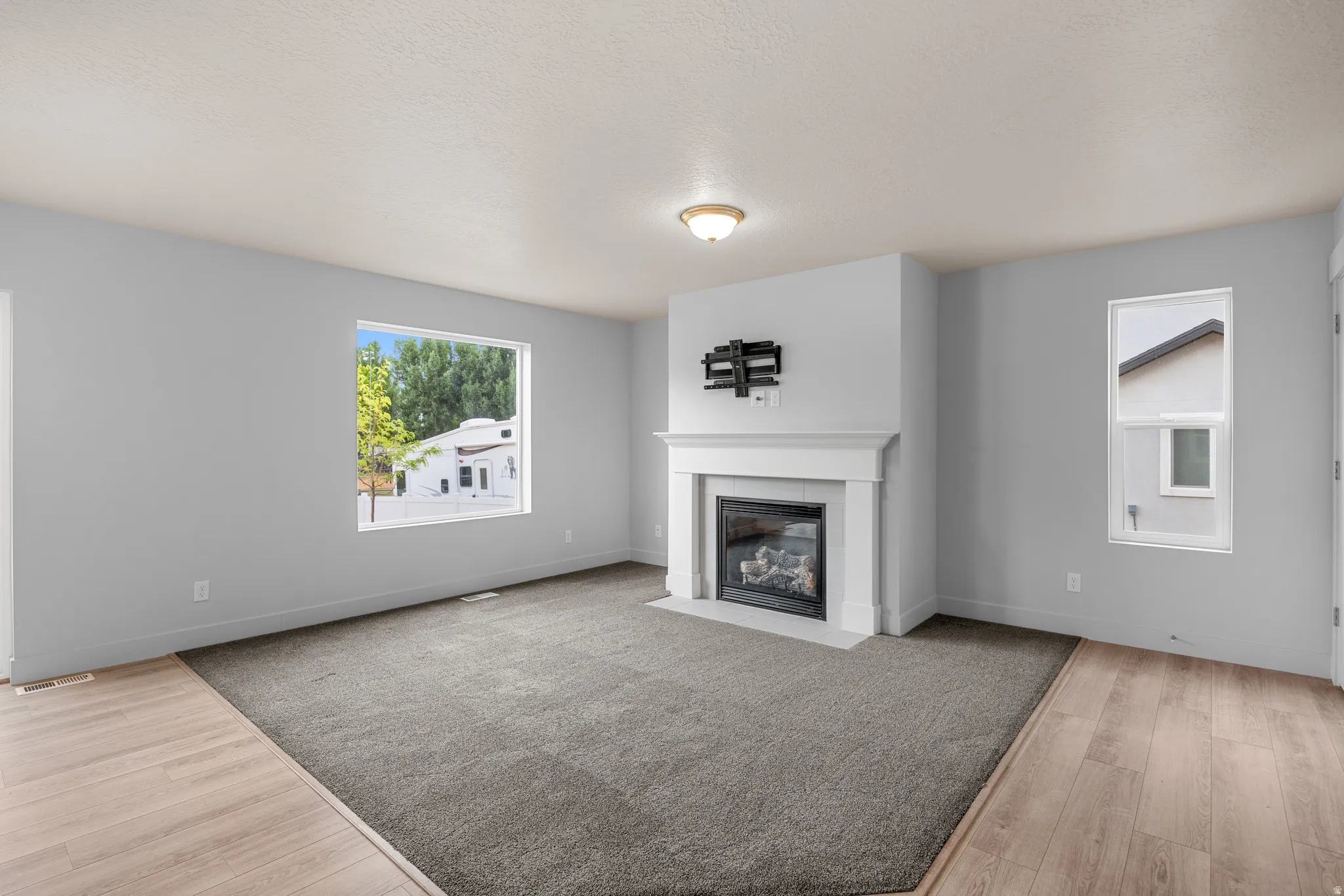 Unfurnished living room with light wood-type flooring, a fireplace, and a textured ceiling
