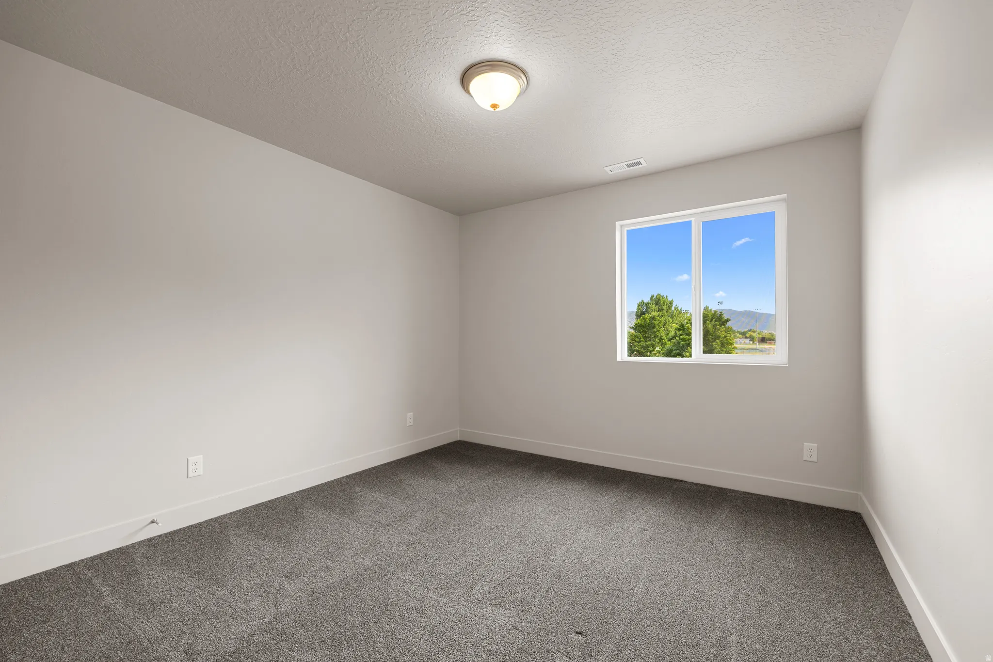 Unfurnished room featuring dark carpet and a textured ceiling