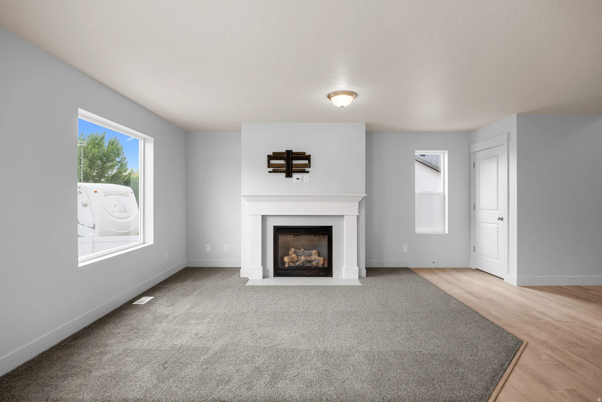 Unfurnished living room featuring a fireplace with flush hearth and plenty of natural light
