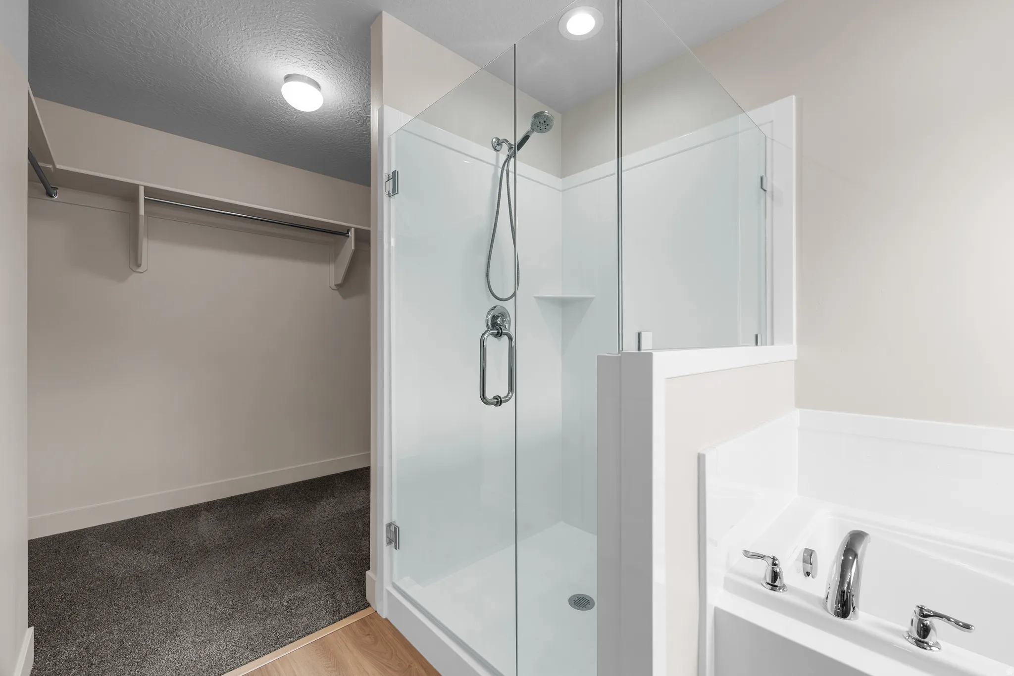 Full bathroom with a spacious closet, a stall shower, a bath, light wood finished floors, and light carpet